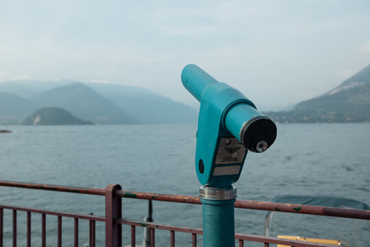 Metal viewing binoculars installed on a promenade for tourists to enjoy scenic panorama and nature landscape during vacation trip.