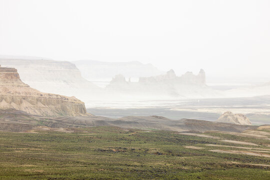 Aerial view of the dramatic limestone formations of Bozjyra, featuring eroded cliffs, vast desert plains, and hazy atmospheric conditions in Aktau, Mangystau Region, Kazakhstan.