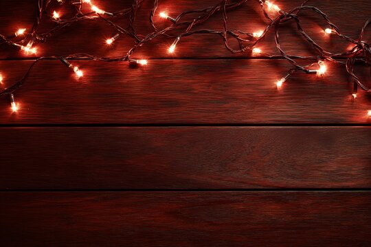 A string of warm, glowing Christmas lights draped across a rustic wooden surface. The lights cast a cozy and festive ambiance, perfect for holiday decorations or seasonal greetings