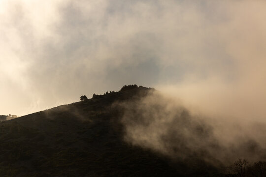 Paysage de montagne, un sommet dans les nuages, brume matinale au lever du soleil