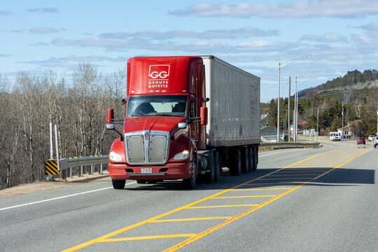 Quebec, Canada, 24 April 2026 : A red Groupe Goyette semi-truck with a white trailer drives on a highway under a blue sky.