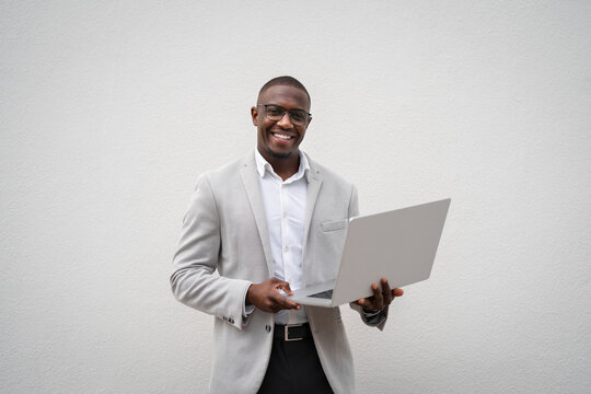 Using laptop, reviewing budget, black businessman isolated studio background, works as real estate agent. African business man smiling, committed to career growth, managing accounts. Copy space