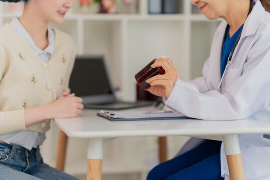Female doctor explaining spine model to a young patient with blue hair in a clinic, medical consultation about back pain or posture correction.