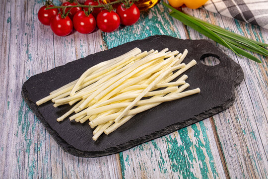 String cheese sticks on black slate with cherry tomatoes and green onions