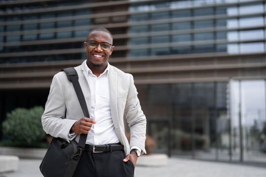 Business owner african american businessman outdoor near office building, holding bag. Black business man smiling, staying productive throughout day, building strong client partnerships. Copy space