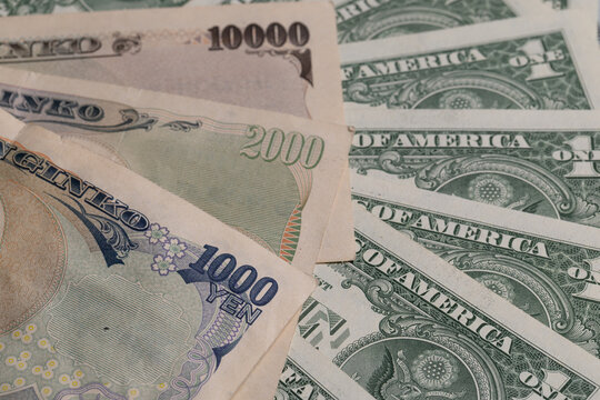 Japanese yen banknotes fan out next to US one dollar bills background