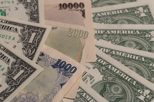 Japanese yen banknotes fan out next to US one dollar bills background