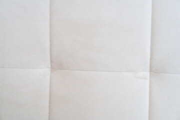 Fototapeta premium Close-up of a light cream tufted fabric upholstery texture with stitched square seams