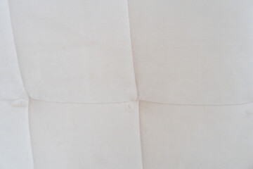 Fototapeta premium Close-up of a light cream tufted fabric upholstery texture with stitched square seams