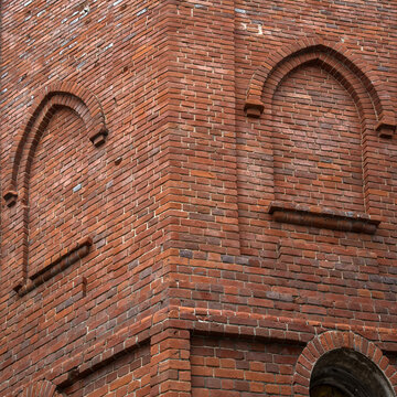 A fragment of the corner of an old building dating back to the early 20th century is made of red brick in the neo-Gothic style.