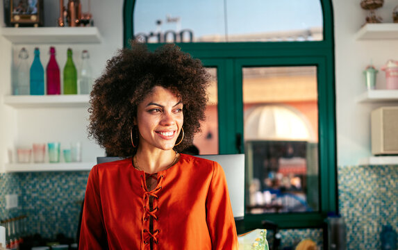 Joyful young woman enjoys summer travel, smiling confidently from behind a colorful retail counter