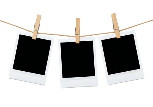 Three empty instant photo frames hanging on a clothesline with polaroid