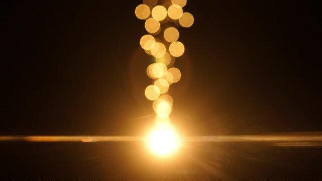 Abstract golden bokeh lights on a dark background with lens flare effect