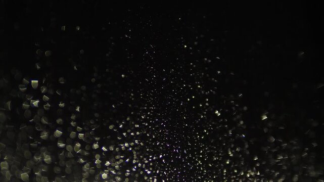 Raindrops on night glass are illuminated by soft city lights and headlights. Abstract blurred texture creates a cozy and melancholic rainy mood.