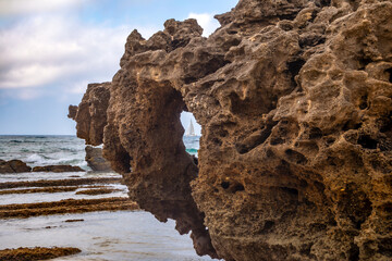 View of a sailing boat through a hole in a rock on Bolonia beach, Cádiz, Andalusia, Spain © AntonioLopez