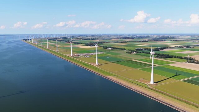 Aerial drone view of offshore and onshore wind turbines. Sustainable green power station for clean electricity production on land and sea.