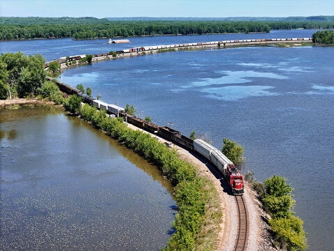 Savanna, Illinois May 14, 2026 Canadian Pacific 2326 Locomotive pulling freight curving Along the Mississippi River with a barges in the distance.