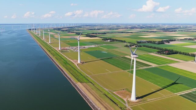 Aerial drone view of offshore and onshore wind turbines. Sustainable green power station for clean electricity production on land and sea.
