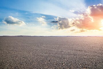 Obraz premium Vast empty gravel desert plain under a dramatic sky with bright sunbeams