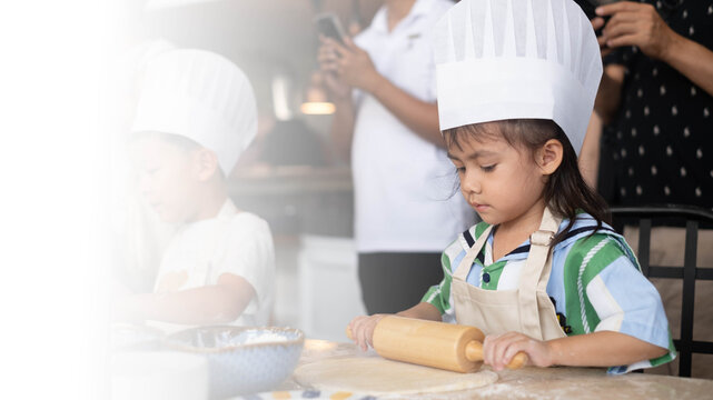 Little girl wearing a chef hat and apron rolling dough in a children's baking class. Hands-on cooking activity inspires creativity, confidence, early education, family bonding, practical life skills.