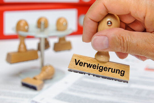 Eine Hand h&auml;lt einen Holzstempel mit der Aufschrift: Verweigerung