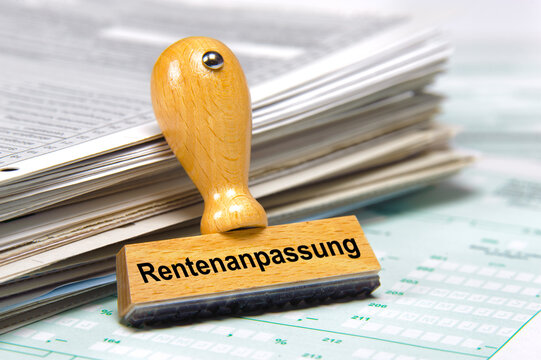 An einem Stapel Formulare lehnt ein Holzstempel mit dem Aufdruck: Rentenanpassung