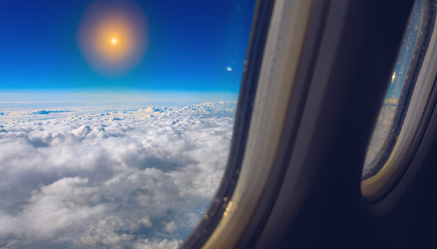 A breathtaking view of a bright glowing sun and fluffy white clouds seen through an airplane window evokes pure freedom and wanderlust. Ideal for travel concepts, with no people.