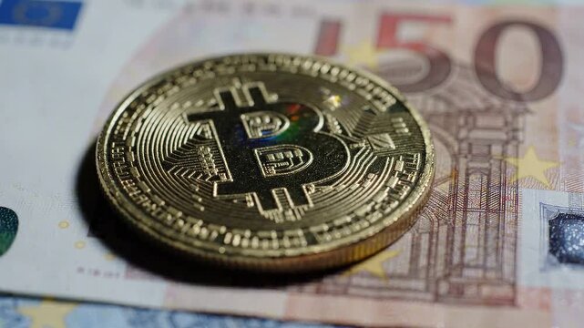 A physical gold bitcoin coin placed on top of a 50 euro banknote, representing the intersection of cryptocurrency and traditional fiat currency