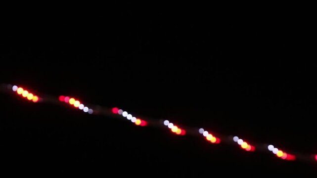 Abstract blurred string of red and white festive lights against a black background.