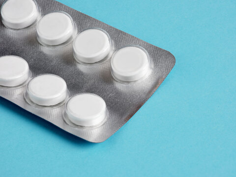 Blister Pack Containing Round White Pills Lying on a Light Blue Background