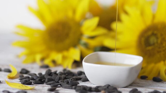 Fresh yellow sunflower blossoms near bowl of pure organic oil video