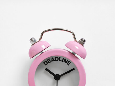 Pink alarm clock showing deadline approaching on white background