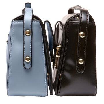 Side view of blue and black leather women handbags isolated on white background. Pair of stylish female purses with gold metal rivets