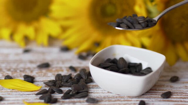 Spoon over sunflower seeds bowl next to bright sunflower footage