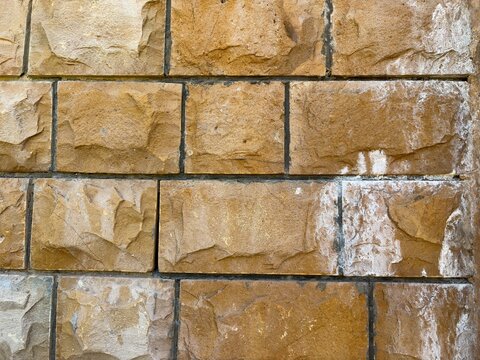 Rustic rough cut stone block wall texture background with chiseled masonry blocks