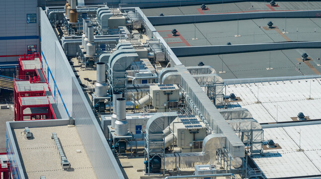 Aerial view of large rooftop HVAC systems, ventilation ducts and air handling equipment installed on a modern high-tech manufacturing facility in Crolles, Auvergne-Rhone-Alpes, France.