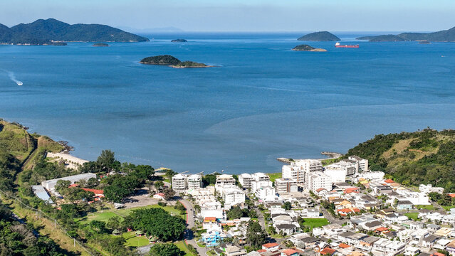 Aerial view of Reserva do Sahy, Condado with coastal residential buildings, lush green hills, and a sandy beach overlooking the blue ocean in Mangaratiba, Rio de Janeiro, Brazil.