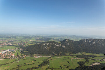 Fototapeta premium Wide alpine valley with town fields and distant mountains