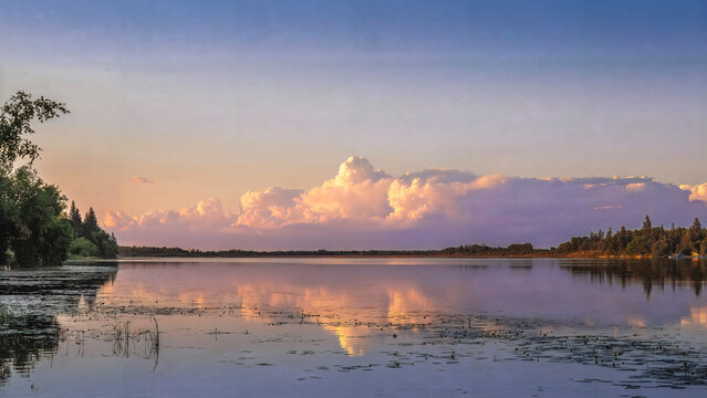 Golden Sunset Reflecting on a Calm Northern Lake Beneath Towering Storm Clouds