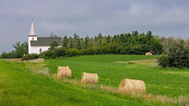 Classic White Prairie Church with Round Hay Bales at Bergheim, Saskatchewan, Canada