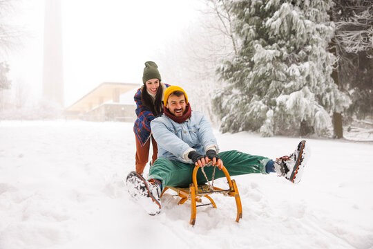 Woman pulling man on the sledge while on winter vacation