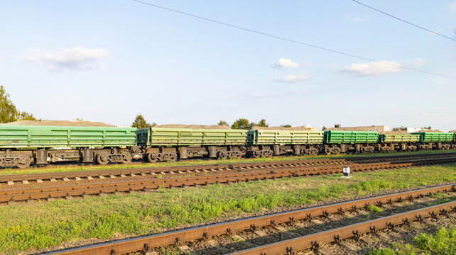 Railway wagons. Green hopper dump cars for bulk cargo standing on multiple railroad tracks. Concept of heavy industrial logistics, raw material transport
