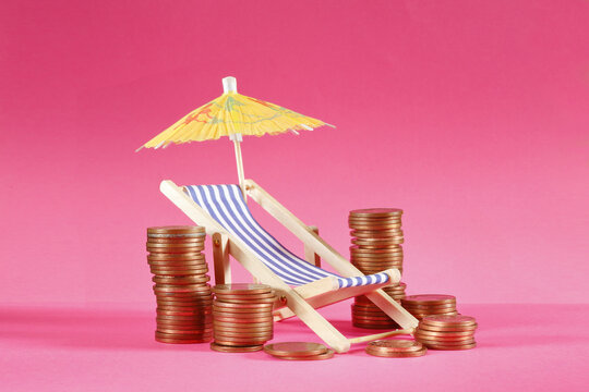 rising prices for vacation and summer holidays or wealth management concept with stacks of coins deckchair and sun umbrella