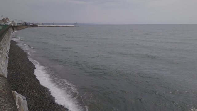 Views over the sea at Penzance seafront on a hot overcast muggy June day during high tide.