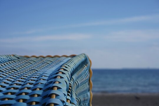 Blauer Strandkorb im Fokus vor dem blauen Himmel und Meer der Ostsee in der L&uuml;becker Bucht