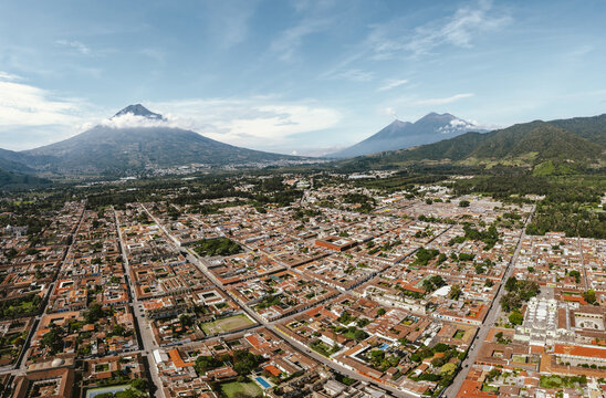Aerial view of the historic city of Antigua Guatemala with colonial architecture and red-tiled roofs, framed by majestic volcanoes in Antigua Guatemala, Sacatepequez Department, Guatemala.