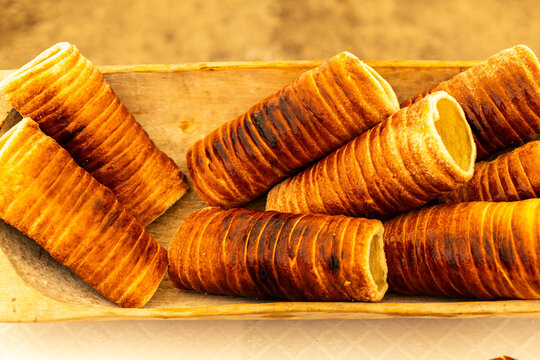 Freshly baked chimney cakes or traditional kurtos kalacs Hungarian cake pastries arranged in a wooden trough