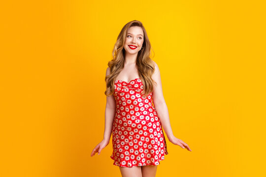 Young woman in red floral dress smiling against bright yellow background, summer fashion portrait conveying joy and carefree style