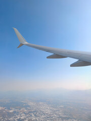 Fototapeta premium Airplane Wing Above the Clouds During Flight. Cinematic Airplane Wing and Cloudscape. Commercial Airliner Wing Over the Sky Clouds.