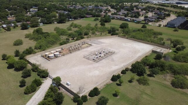 Industrial gas facility borders busy retail strip along Wilshire Blvd near Fort Worth. Aerial perspective showcases energy equipment beside suburban commercial development in Burleson, TX